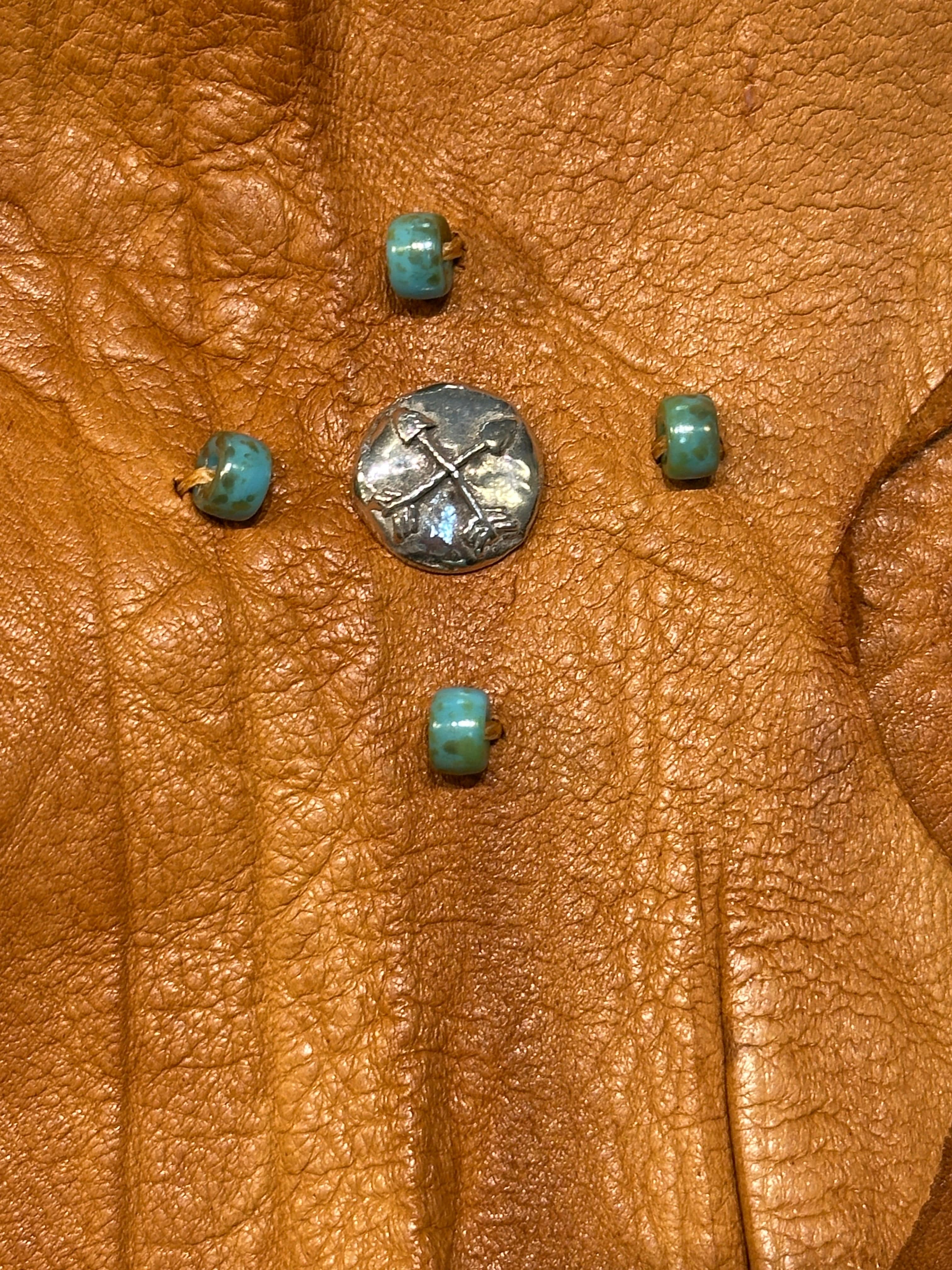 Detail of Elk Leather Crossbody showing sterling silver button with two crossed arrows. The button has 4 hand sewn turquoise beads around it. Handcrafted byBridger Leather
