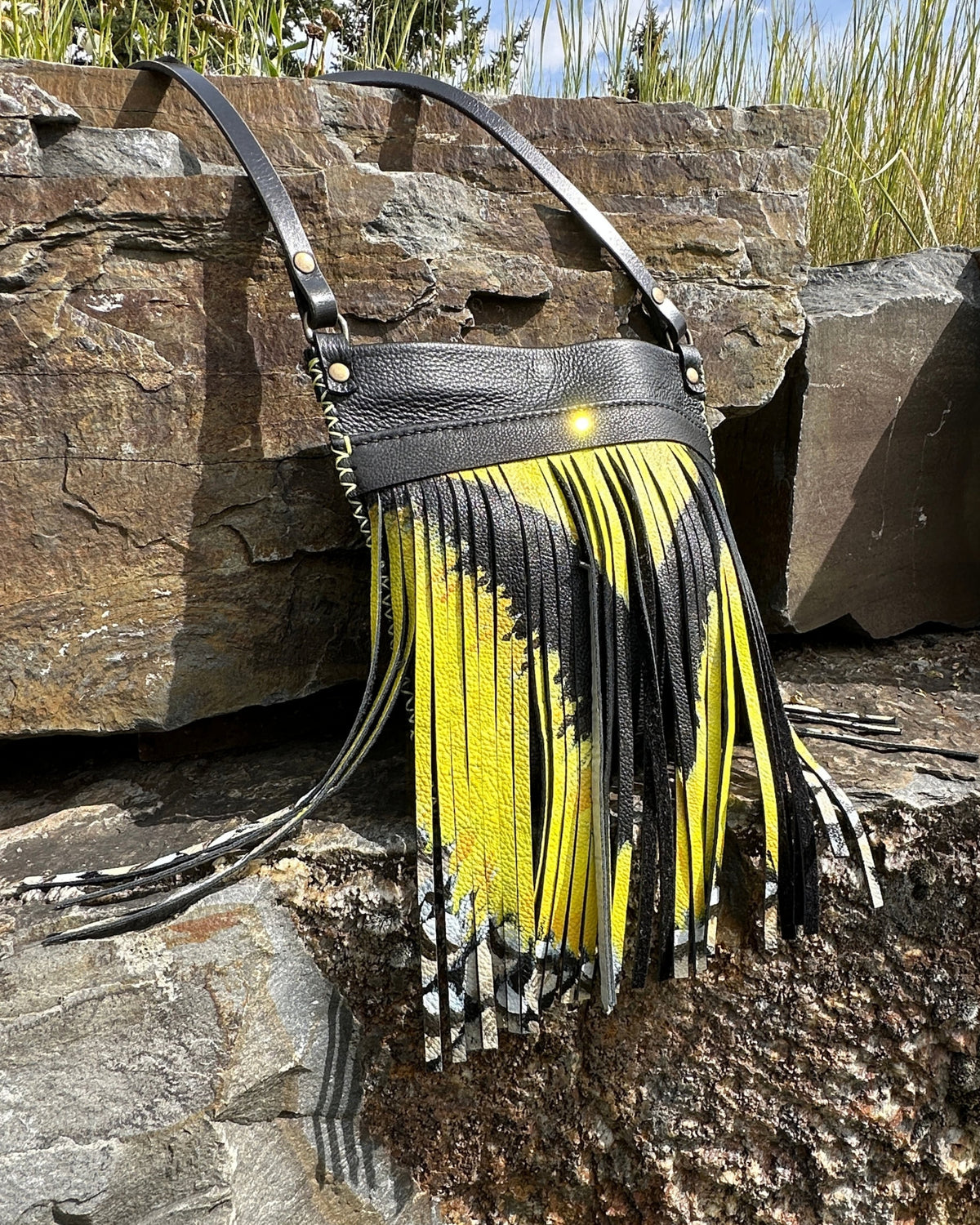 Side angle of the MeadowLark Crossbody showing the hand-cut fringe painted with the meadowlark's yellow breast and streaked flanks