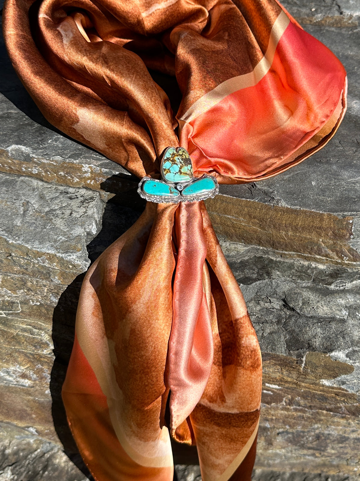 Spiderweb turquoise cowgirl hat ring as a scarf slide on the Absaroka silk scarf in rust, copper and coral, tied wild rag style