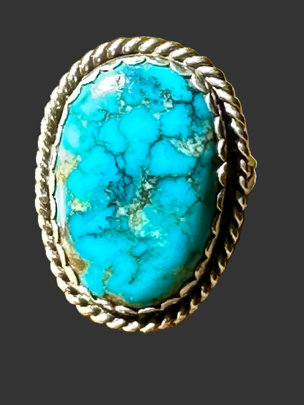Sterling silver and turquoise ring with a twisted-rope bezel, shown in warm sunlight on brown leather