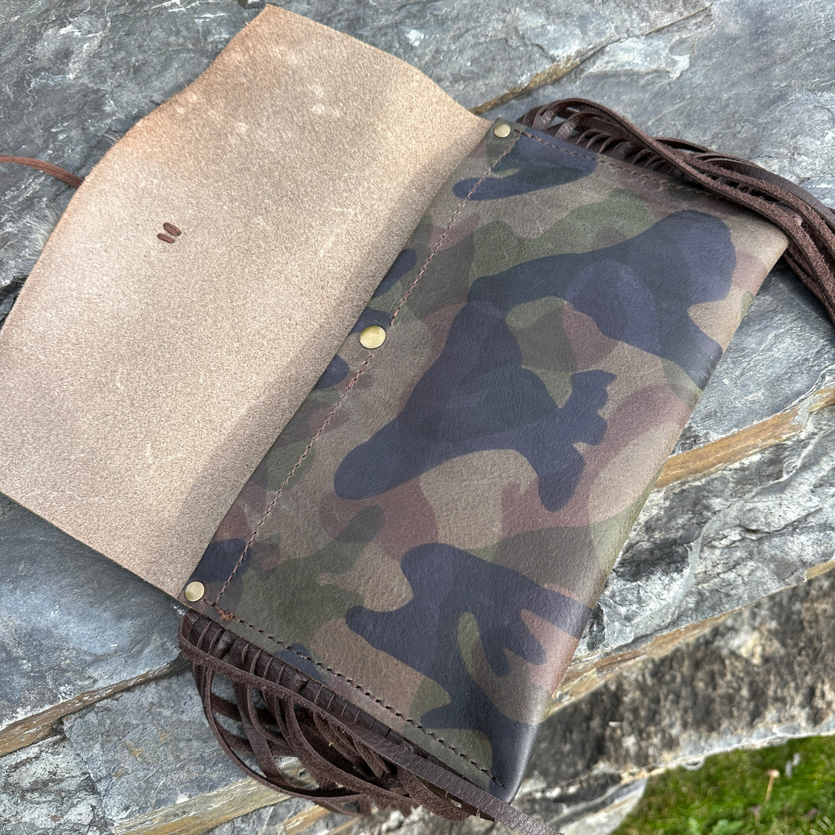 Interior view of the Upland Camo Leather Clutch by Bridger Leather, open to show the natural leather lining, camo-printed exterior, and leather fringe trim