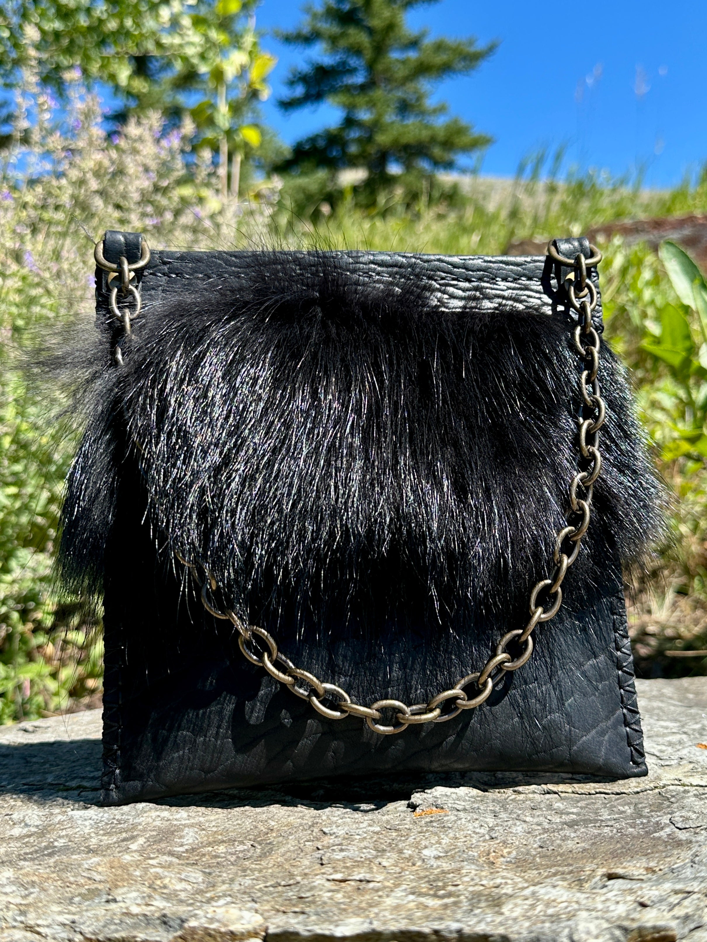 Front view of the Ana Evening Bag showing the black coyote fur trim and pebbled black bison leather body