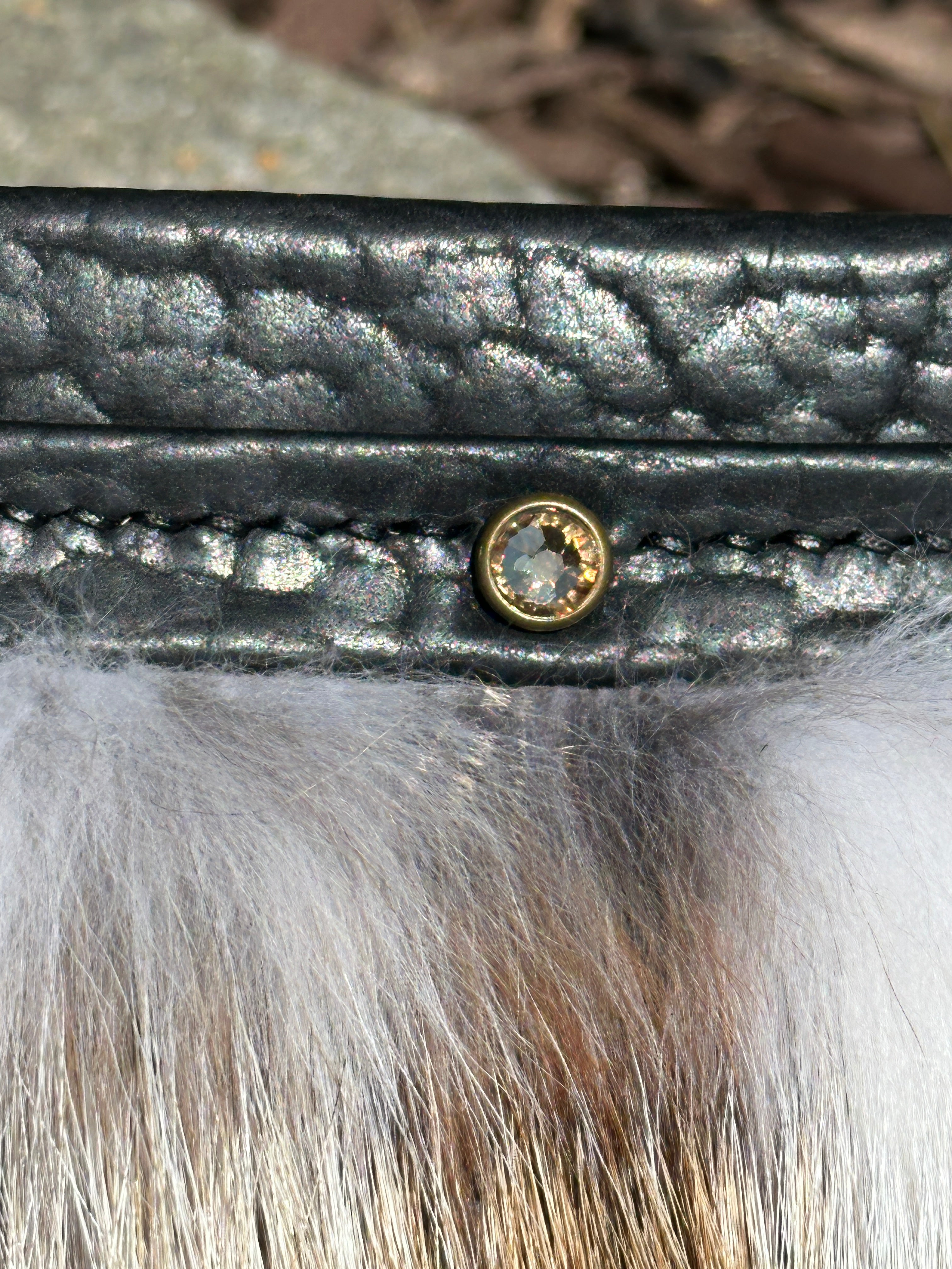 Close-up of the Ana Evening Bag's Swarovski crystal accent, brass rivet, pebbled bison leather, and fox fur trim