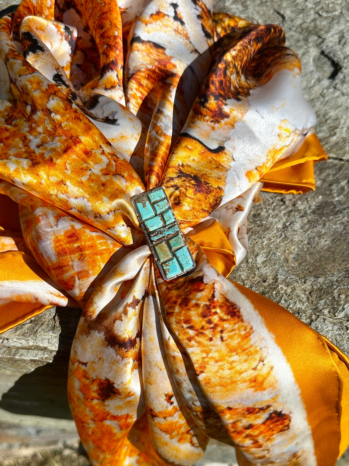 Brandon Etsitty turquoise cobblestone ring worn as a scarf slide on the orange, gold and cream Mammoth Hot Springs silk scarf