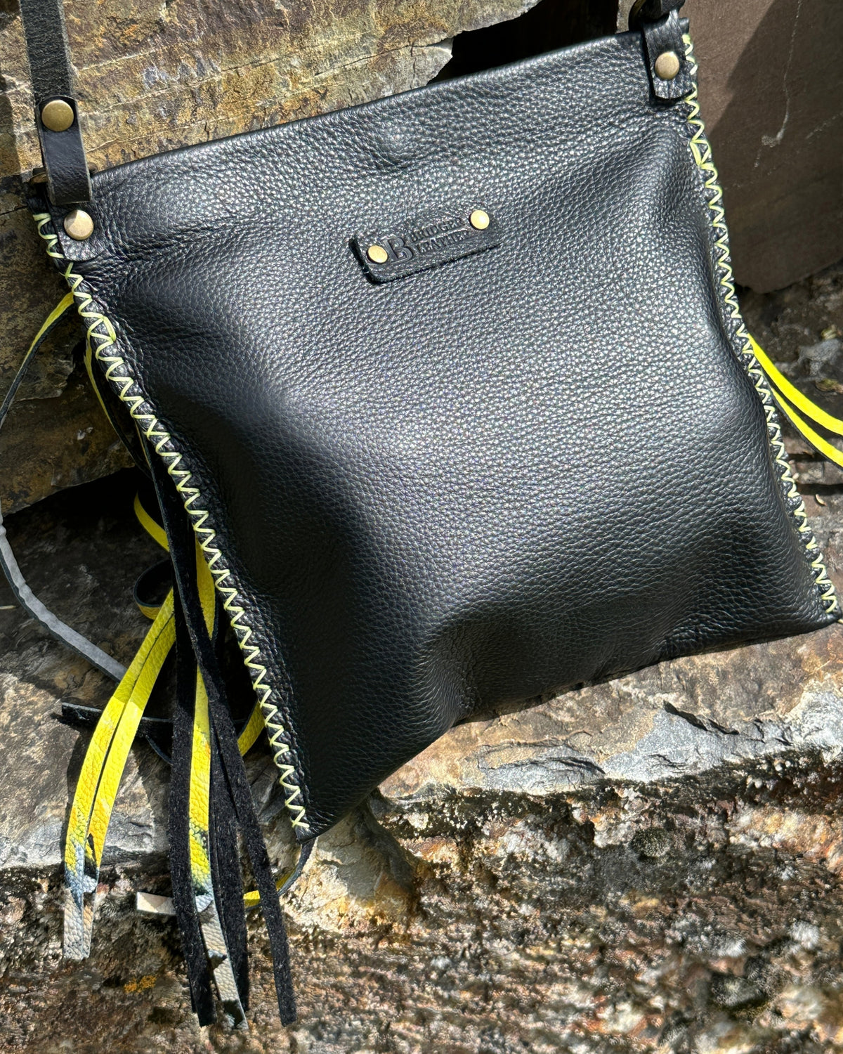 Back of the MeadowLark Crossbody in black pebbled cow leather with yellow whipstitched side seams