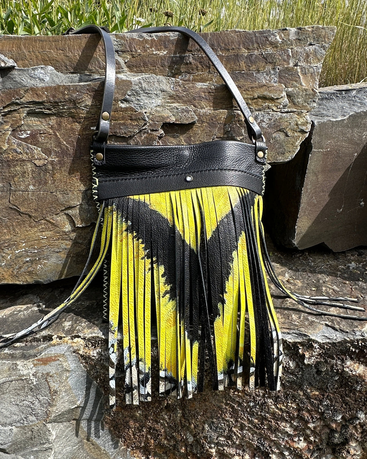 MeadowLark Crossbody with its black leather strap and antique brass hardware, showing the painted meadowlark fringe