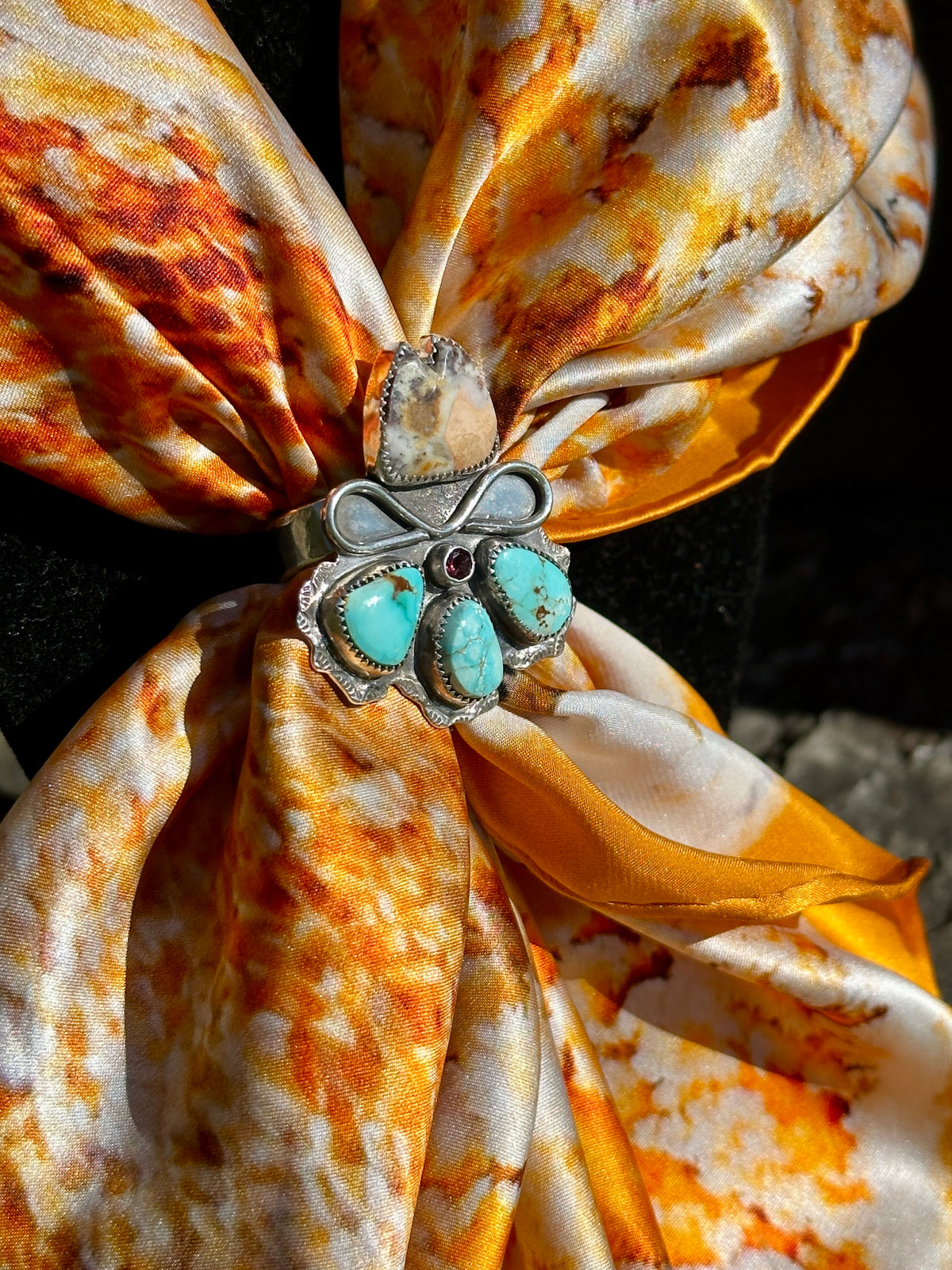 Jasper and ruby cowgirl hat ring worn as a scarf slide on the Mammoth Hot Springs silk scarf in orange, gold and cream