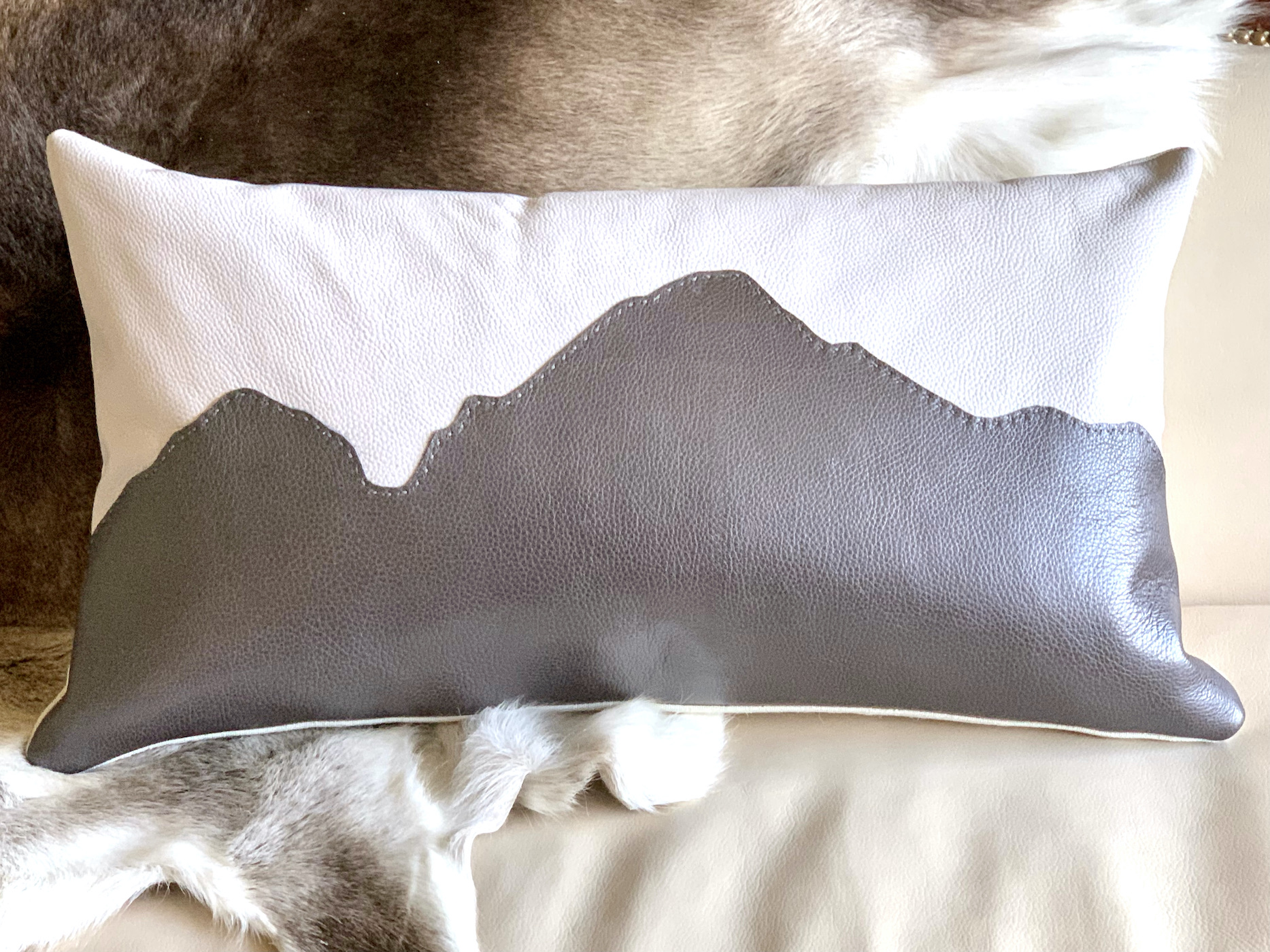 White and platinum leather pillow with a mountain range applique, symbolizing Camelback Mountain in Scottsdale, Arizona.